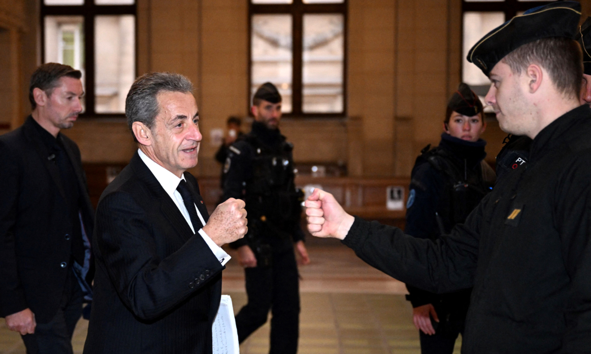 Former French president Nicolas Sarkozy (second left) gives a fist bump with a French gendarme as he arrives at the courthouse on the third day of the appeal hearing of a corruption trial at Paris courthouse on December 8, 2022. A French court in 2021 convicted the former president on charges of corruption and influencing peddling. Photo: AFP