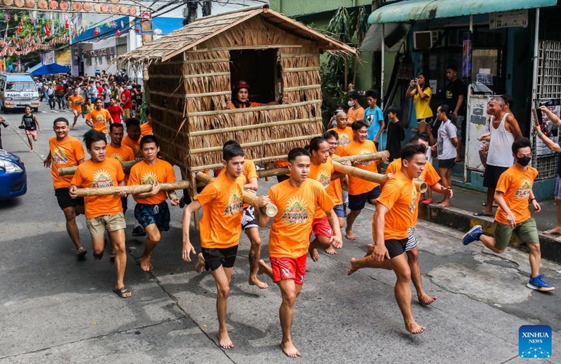 Residents run while carrying a hut made out of nipa palm during the Buhat Kubo (nipa hut carrying) race in Pasig City, the Philippines, Nov. 12, 2022. (Xinhua/Rouelle Umali)