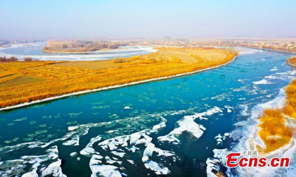 2022 年 12 月 15 日，在中国西北部的新疆维吾尔自治区和静县，鸟瞰图显示浮冰漂浮在开都河上，河岸上积雪。照片：中新社