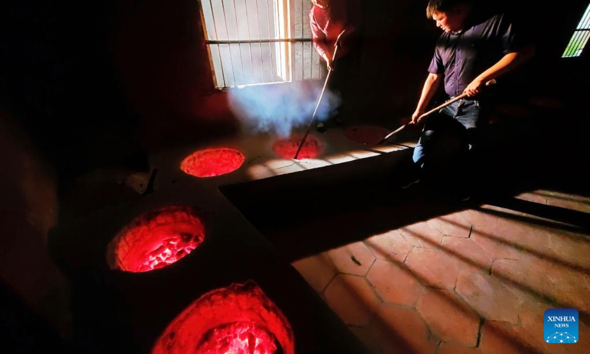 You Yuqiong (L), the only female inheritor of Wuyi rock tea making technique, instructs her son Fang Zhou in the charcoal roasting technique of Wuyi rock tea in Wuyishan, southeast China's Fujian Province, May 10, 2020. Photo:Xinhua