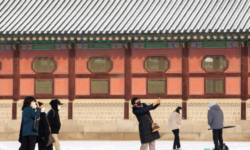 Tourists take photos at the Gyeongbokgung Palace in snow in Seoul, South Korea, Dec. 3, 2022. (Xinhua/Wang Yiliang)