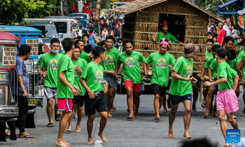 Residents run while carrying a hut made out of nipa palm during the Buhat Kubo (nipa hut carrying) race in Pasig City, the Philippines, Nov. 12, 2022. (Xinhua/Rouelle Umali)