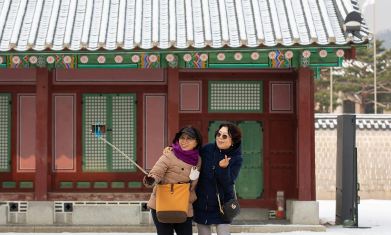 Tourists take photos at the Gyeongbokgung Palace in snow in Seoul, South Korea, Dec. 3, 2022. (Xinhua/Wang Yiliang)