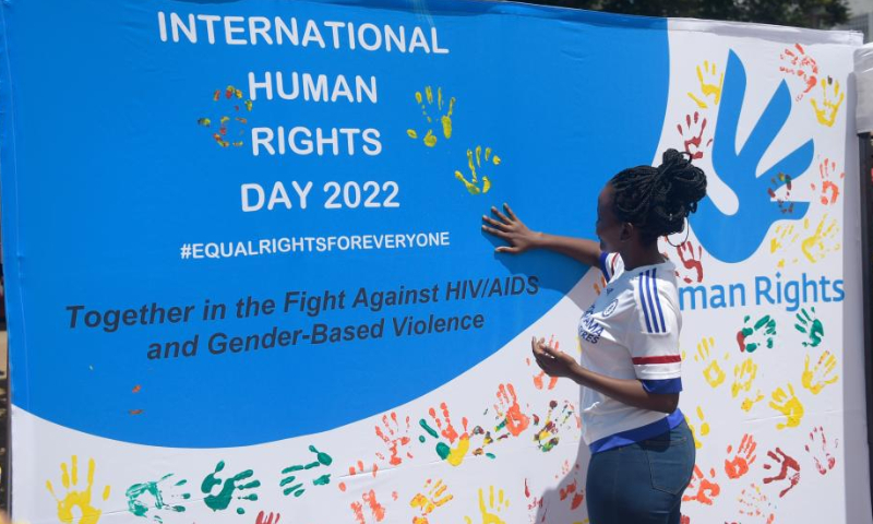 A woman applies paint to a banner during a public event to commemorate the Human Rights Day in Gaborone, Botswana on Dec. 9, 2022. Human Rights Day is observed every year on Dec. 10 - the day the United Nations General Assembly adopted in 1948 the Universal Declaration of Human Rights. (Photo by Tshekiso Tebalo/Xinhua)