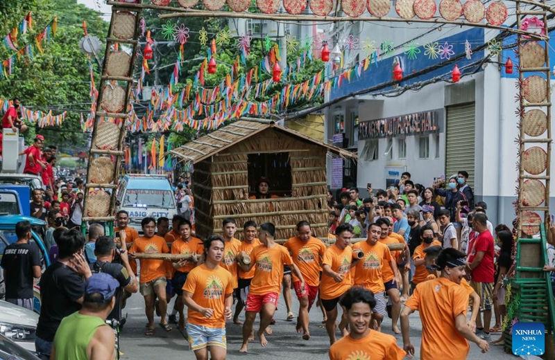 Residents run while carrying a hut made out of nipa palm during the Buhat Kubo (nipa hut carrying) race in Pasig City, the Philippines, Nov. 12, 2022. (Xinhua/Rouelle Umali)