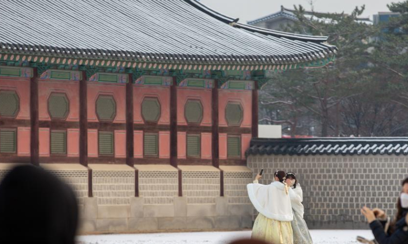 Tourists take photos at the Gyeongbokgung Palace in snow in Seoul, South Korea, Dec. 3, 2022. (Xinhua/Wang Yiliang)