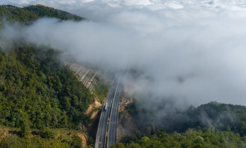 This aerial photo taken on Dec. 10, 2022 shows a vehicle running on a road amid sea of clouds in Lincang City of southwest China's Yunnan Province. (Xinhua/Jiang Wenyao)