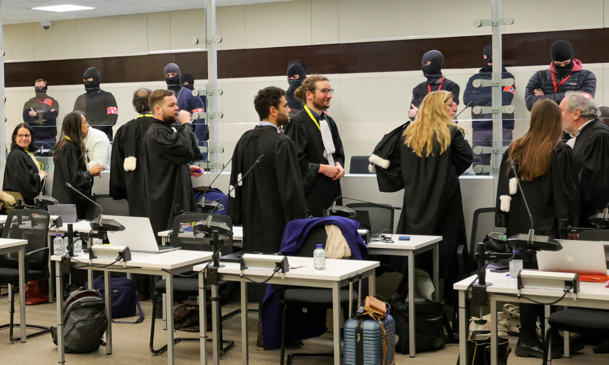 Defense lawyers talk to defendants through a specially designed glass box in the courtroom before the start of the trial of alleged jihadists accused of directing or aiding suicide bombings in Brussels’ metro and airport on March 22, 2016, at the Justitia building in Brussels, Belgium on December 5, 2022. Photo: VCG