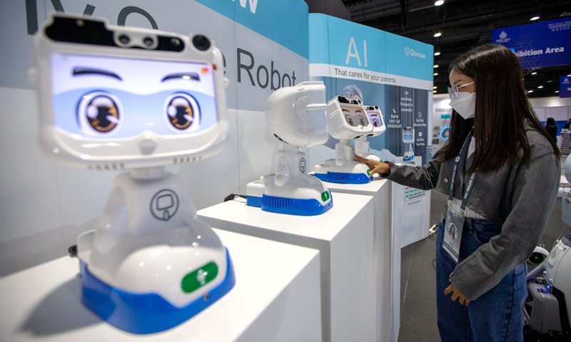 A staff member interacts with a robot at the Queen Sirikit National Convention Center in Bangkok, Thailand, on Nov. 14, 2022. (Xinhua/Wang Teng)