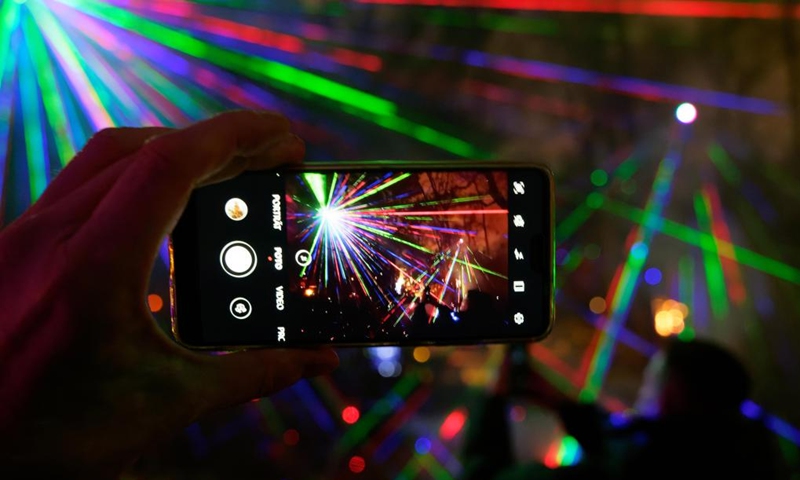 A visitor takes photos of light decorations during the Christmas Garden Berlin light show at the Botanical Garden in Berlin, Germany, Nov. 16, 2022. The Christmas Garden Berlin kicked off on Wednesday here and will last until Jan. 15, 2023. (Photo by Stefan Zeitz/Xinhua)