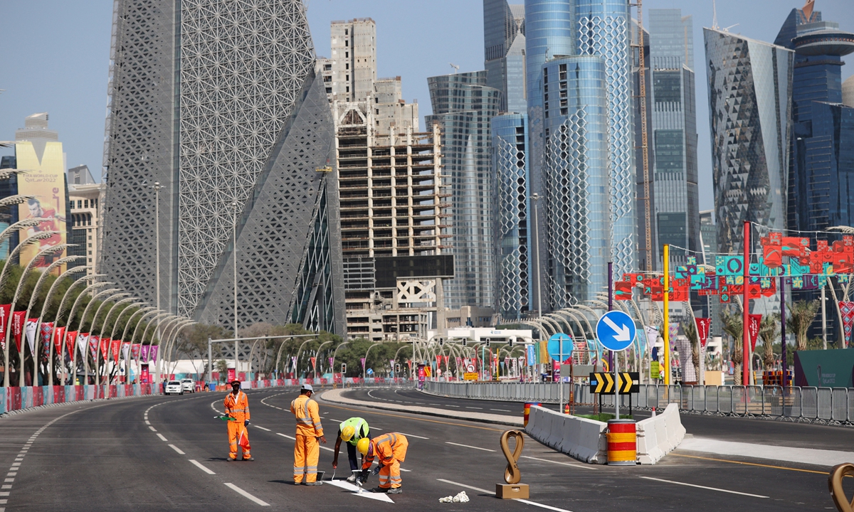 Workers paint direction signs on the road on the Corniche in Doha, Qatar on November 14, 2022. Photo: AFP