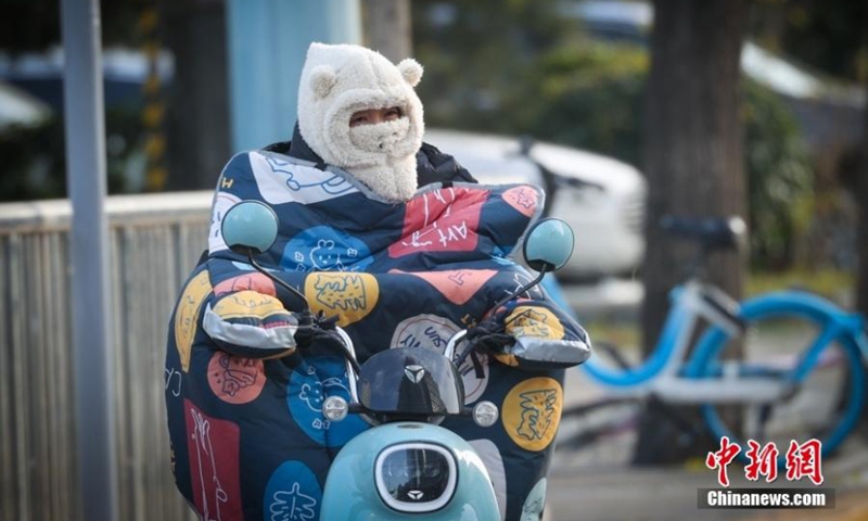 A resident wearing heavy clothing rides an electric bike on the road amid the cold wave in Beijing, Nov. 28, 2022. China on Tuesday continued to issue an orange alert for a cold wave, forecasting big temperature drops and gales in vast regions. (Photo: China News Service/Jia Tianyong) 