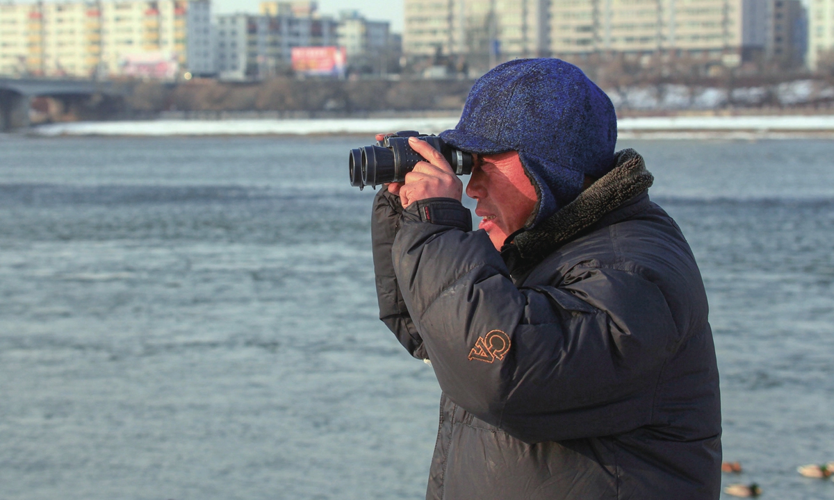 Ren Jianguo holds a telescope to watch birds at Changbai Island