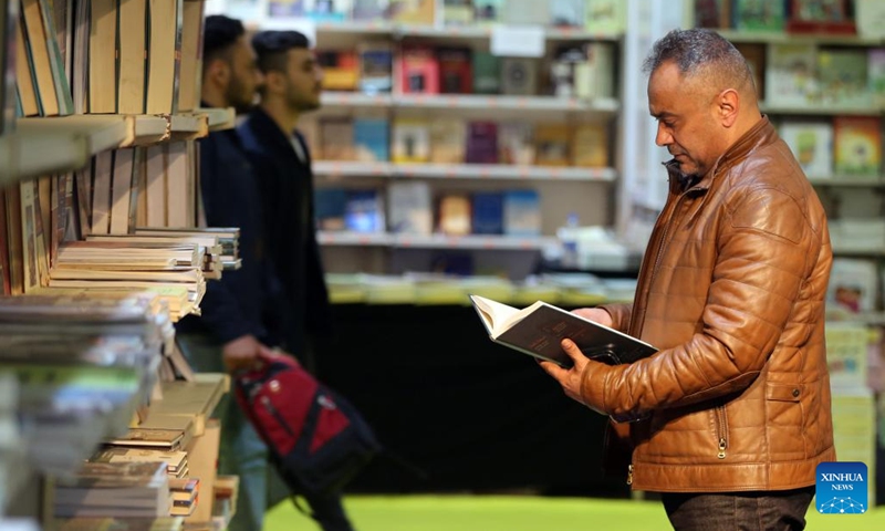 A visitor reads a book at the Iraq International Book Fair in Baghdad, Iraq, on Dec. 7, 2022. Iraqi Prime Minister Mohammed Shia' al-Sudani on Wednesday opened the third edition of the Iraq International Book Fair that has attracted 350 Iraqi and foreign publishing houses from 20 countries.(Photo: Xinhua)