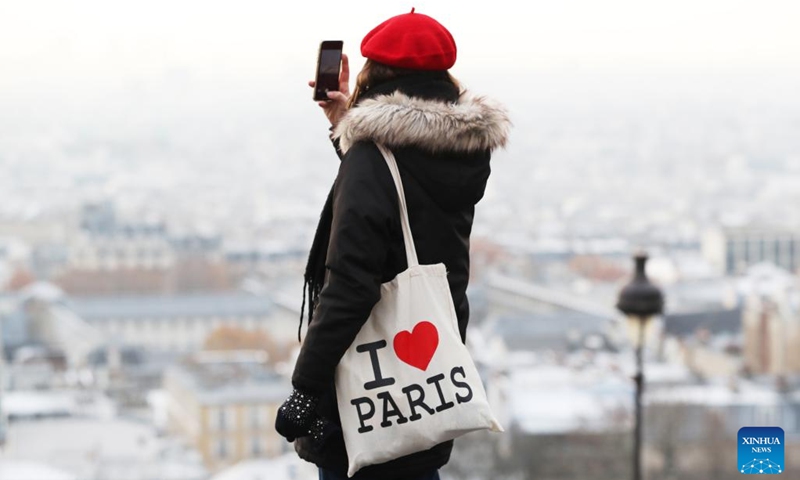 A woman takes photos of the city of Paris covered with snow at the Montmartre in Paris, France, Dec. 14, 2022.(Photo: Xinhua)