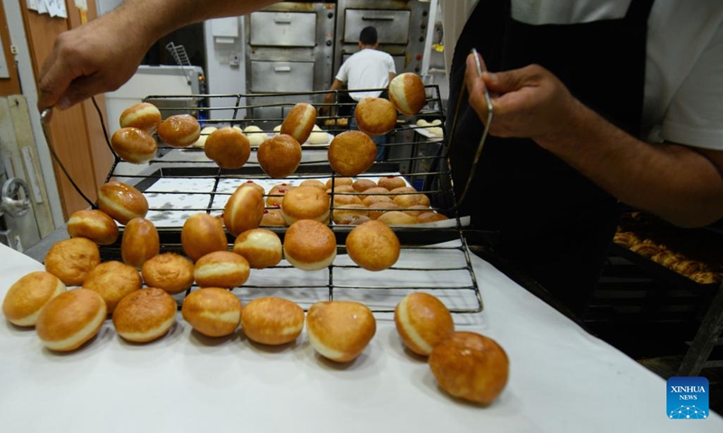 A bakery worker makes sufganiyot, round jelly donuts eaten during the Jewish festival of Hanukkah, at a bakery in Kiryat Shmona, northern Israel, on Dec. 14, 2022.(Photo: Xinhua)