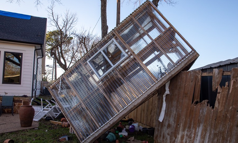 This photo taken on Dec. 14, 2022 shows a green house sitting above the fence after a tornado in Grapevine, Texas, the United States.(Photo: Xinhua)