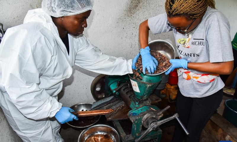 Suzanne Ayolo (L) and her collaborator extract cocoa oil and butter at her cocoa bean processing unit in Minkang II village of Meyomessi subdivision, Cameroon, on Dec. 6, 2022. (Photo by Kepseu/Xinhua)