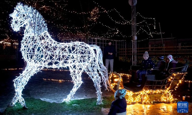 People sit on a light installation at a Christmas light exhibition in Prague, the Czech Republic, on Dec. 22, 2022.(Photo: Xinhua)