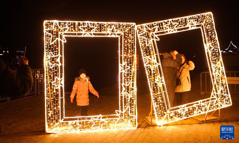 People stand in front of a light installation at a Christmas light exhibition in Prague, the Czech Republic, on Dec. 22, 2022.(Photo: Xinhua)