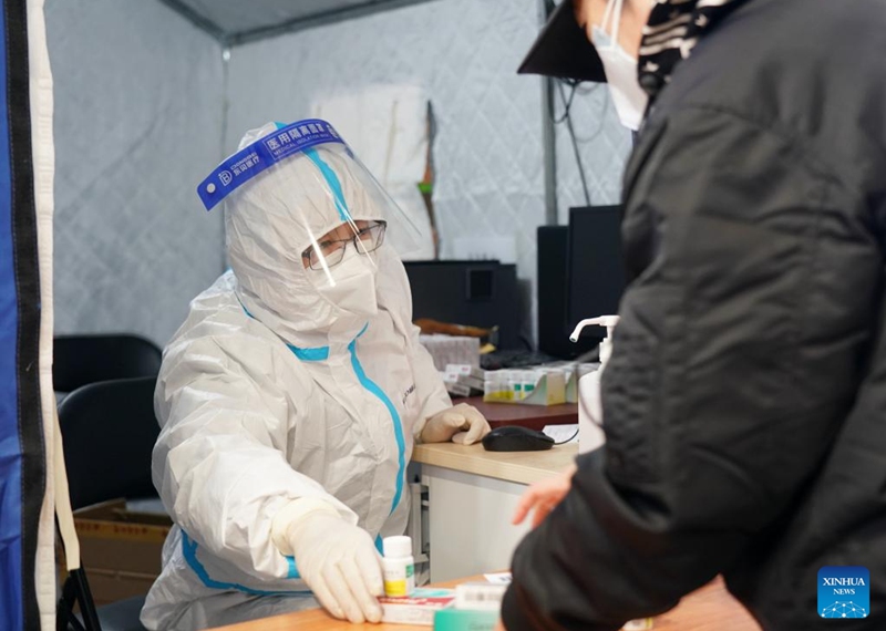 A medical worker passes medicine to a citizen in a makeshift fever clinic in Guang'an Gymnasium in Beijing, capital of China, Dec. 24, 2022. In order to facilitate fever patients to seek medical treatment and ensure residents' medical needs, some hospitals in Beijing set up makeshift fever clinics in gymnasiums to provide services such as diagnosis, prescription issuing and medicine dispensing for citizens. (Xinhua/Zhang Chenlin)