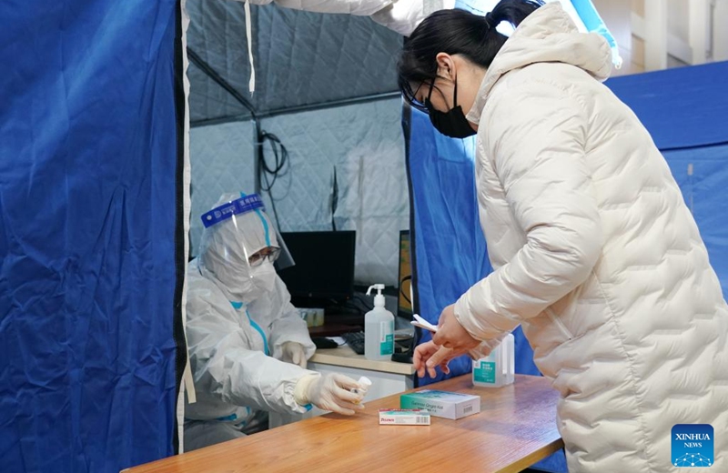 A medical worker passes medicine to a citizen in a makeshift fever clinic in Guang'an Gymnasium in Beijing, capital of China, Dec. 24, 2022. In order to facilitate fever patients to seek medical treatment and ensure residents' medical needs, some hospitals in Beijing set up makeshift fever clinics in gymnasiums to provide services such as diagnosis, prescription issuing and medicine dispensing for citizens. (Xinhua/Zhang Chenlin)