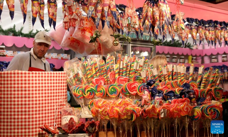 A man sells candies at Hyde Park Winter Wonderland on Christmas Eve in London, Britain, Dec. 24, 2022. (Xinhua/Li Ying)