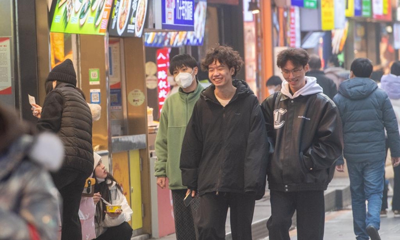 Young people are seen on Bayi street of the Jiefangbei business district in Chongqing, southwest China, on Dec. 23, 2022. (Xinhua/Tang Yi)