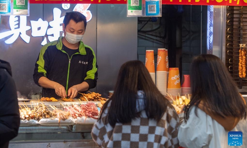 Tourists buy snacks at the Jiefangbei business district in Chongqing, southwest China, on Dec. 23, 2022. (Xinhua/Tang Yi)