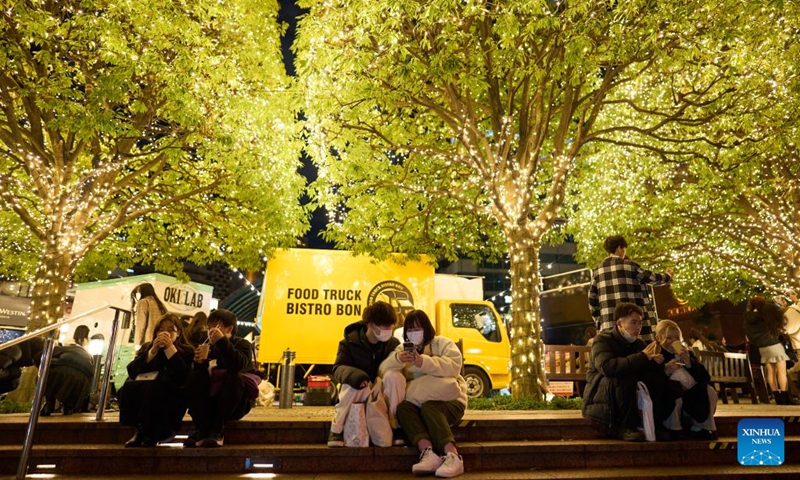 People rest under trees with Christmas lights at the Ebisu Garden Place in Ebisu, Tokyo, Japan, Dec. 25, 2022. (Xinhua/Zhang Xiaoyu)