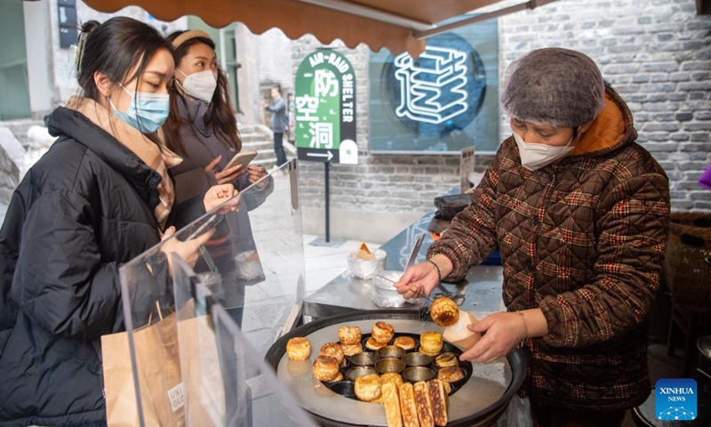 Tourists buy snacks at Shancheng Alley of the Jiefangbei business district in Chongqing, southwest China, on Dec. 24, 2022. (Xinhua/Tang Yi)