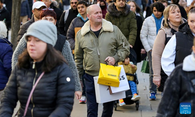 A man is seen with shopping bags on a street during Boxing Day sales in London, Britain, on Dec. 26, 2022.(Photo: Xinhua)