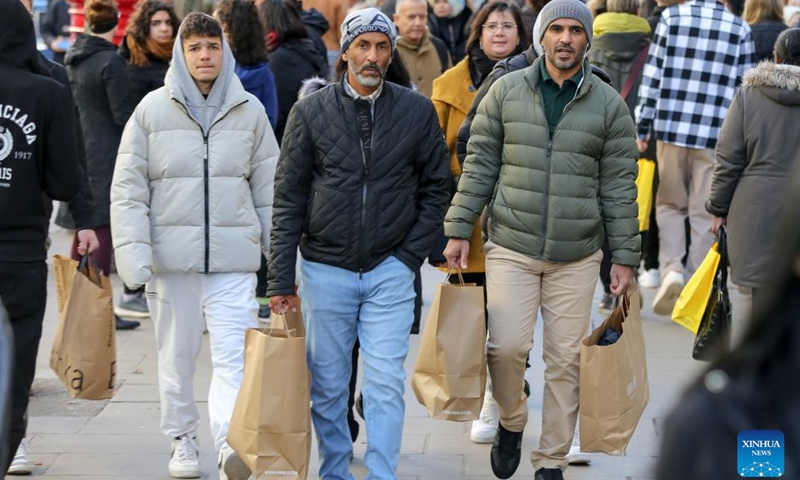 People are seen with shopping bags on a street during Boxing Day sales in London, Britain, on Dec. 26, 2022.(Photo: Xinhua)