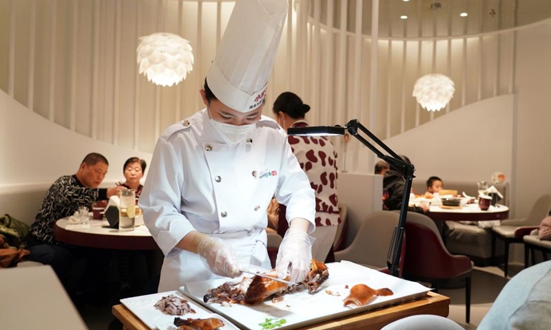 A cook serves roast duck for customers at a restaurant of a shopping mall in Beijing, capital of China, Dec. 25, 2022. In recent days, business areas in Beijing have bustled again as the epidemic prevention and control measures have been optimized in line with the evolving epidemic situation.(Photo: Xinhua)