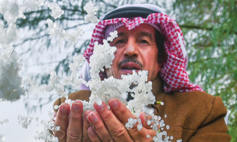 A citizen is seen holding a handful of hailstones after a rare snowfall hit Kuwait City, Kuwait on December 27, 2022. Citizens in Shuaiba and Mina Abd Allah regions experienced great surprise in the country where the air temperature dropped. Photo: VCG