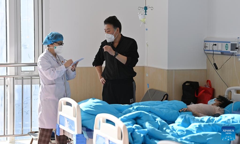 A medical worker questions about a patient's health conditions from her relative in a temporary fever clinic at Traditional Chinese Medicine Hospital of Xiqing District, north China's Tianjin, Dec. 28, 2022. To meet the needs of fever patients seeking medical treatment and relieve the pressure on fever clinics in medical institutions, a temporary fever clinic was recently put into use at the new campus of Traditional Chinese Medicine Hospital of Xiqing District in Tianjin.(Photo: Xinhua)