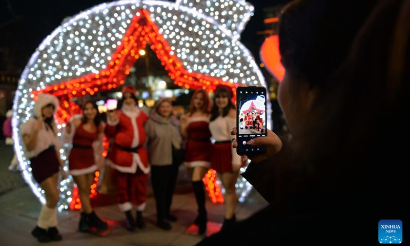 People pose for a group photo with New Year's light decorations in Ankara, Türkiye, Dec. 30, 2022. (Photo by Mustafa Kaya/Xinhua)