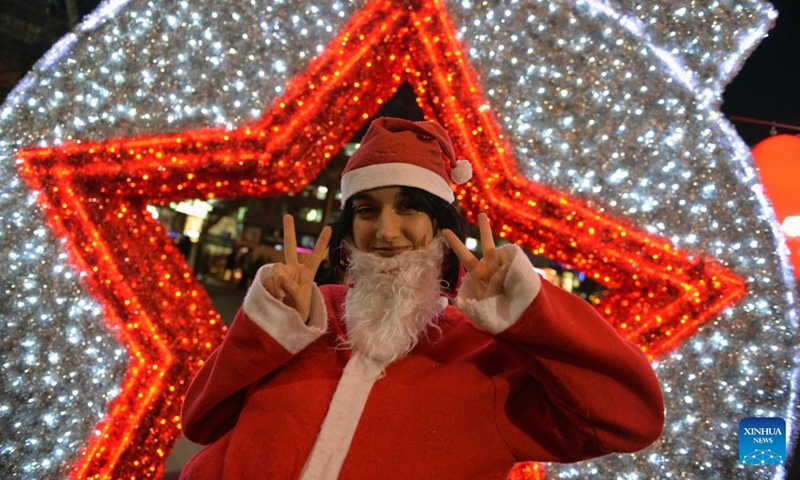 A woman poses for a photo with New Year's light decorations in Ankara, Türkiye, Dec. 30, 2022. (Photo by Mustafa Kaya/Xinhua)