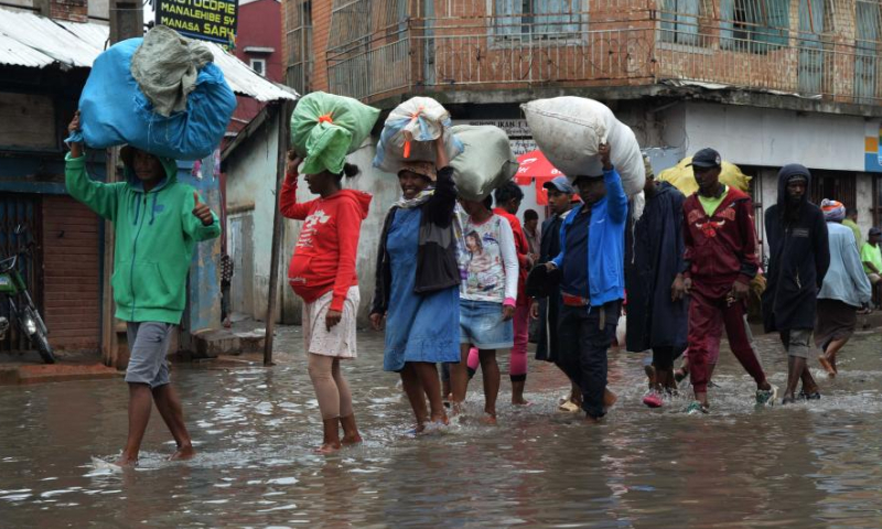 People walk on a flooded road in Antananarivo, Madagascar, on Jan. 25, 2023. The death toll has risen to 16 with 19 people still missing after the strong tropical storm Cheneso hit Madagascar, according to the latest report released Thursday by the National Office for Risk and Disaster Management (BNGRC). Photo: Xinhua