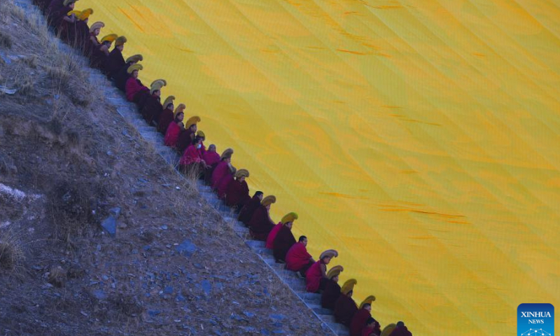 Lamas prepare to uncover the large yellow curtain on a huge thangka scroll bearing the image of the Buddha during the sunning of the Buddha ceremony at the Labrang Monastery in Xiahe County, northwest China's Gansu Province, Feb. 3, 2023. Photo: Xinhua