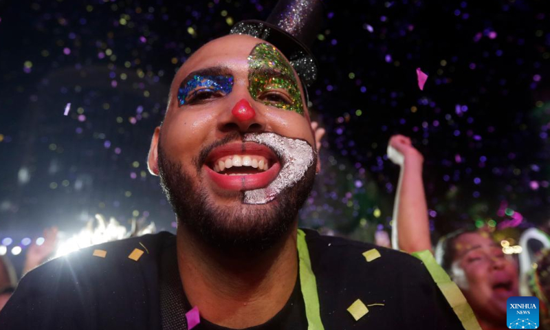 A reveler dressed as a clown smilies while listening to frevo music from Pernambuco, during the inauguration of carnival at Marco Zero in Recife, Pernambuco, Brazil, on Feb. 17, 2023. A carnival with local cultural features kicked off in Recife on Friday. About 25,000 people attended its opening ceremony and parades. Photo: Xinhua