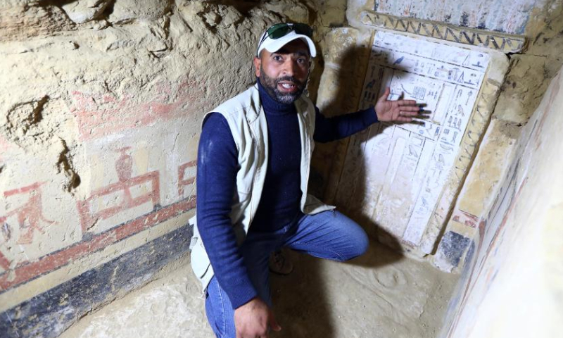 An archaeologist explains the words on a stone inside a newly-discovered ancient tomb in Saqqara necropolis, south of Cairo, Egypt, on Jan. 26, 2023. Egypt's renowned archeologist Zahi Hawass on Thursday announced the discovery of 