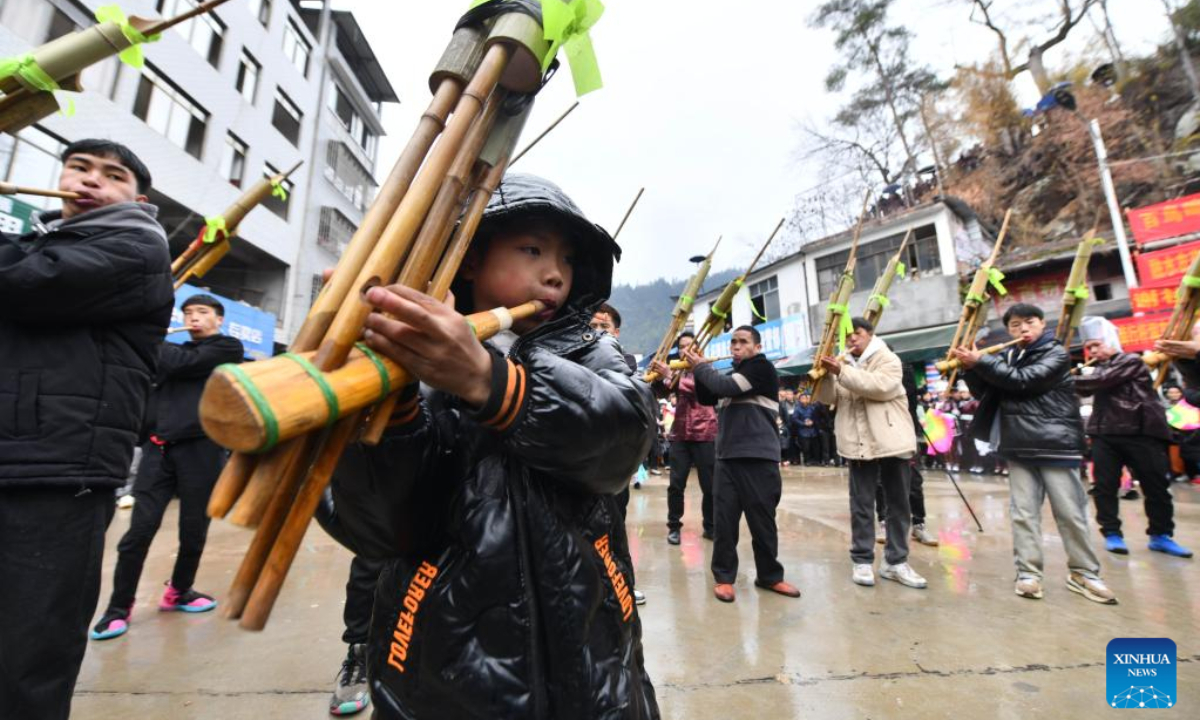 Youngsters of Miao ethnic group blow Lusheng, a traditional reed-pipe wind instrument, during the 