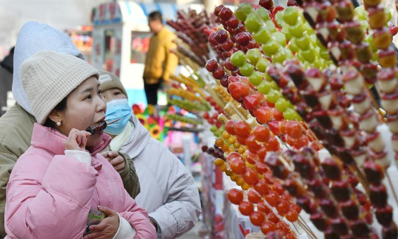 Tourists taste Tanghulu, a traditional Chinese snack of candied fruit, in Houlihua Village of Renqiu, north China's Hebei Province, Feb. 5, 2023. People celebrate the Lantern Festival, the 15th day of the first month of the Chinese lunar calendar, with various traditional customs across the country. Photo: Xinhua