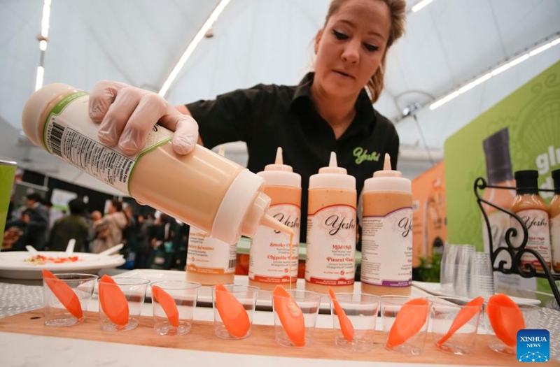 A vendor prepares food samples at a booth during the Gluten Free Expo in Vancouver, British Columbia, Canada, on Jan. 15, 2023. (Photo by Liang Sen/Xinhua)