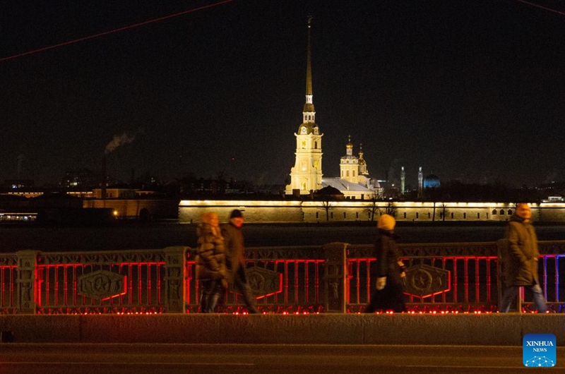 Pedestrians walk on the Palace Bridge which is illuminated in red to celebrate the Chinese New Year in St. Petersburg, Russia, Jan. 21, 2023. (Photo by Irina Motina/Xinhua)