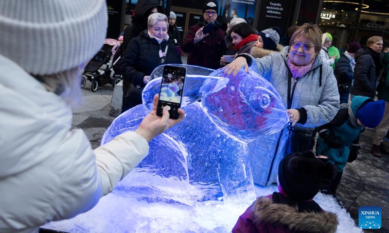 A woman poses for photo with a rabbit-themed ice sculpture made in celebration of the Chinese New Year in Helsinki, Finland, Jan. 21, 2023. (Photo by Matti Matikainen/Xinhua)