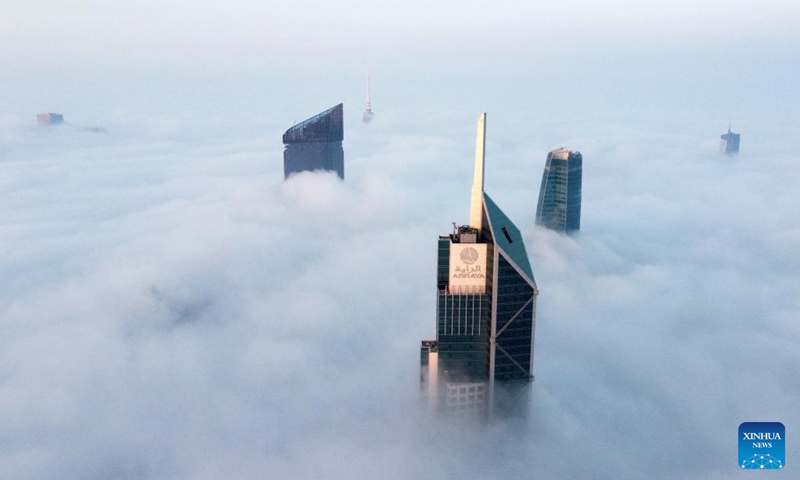 This aerial photo taken on Jan. 21, 2023 shows skyscrapers shrouded by cloud and fog in Kuwait City, Kuwait. (Photo by Asad/Xinhua)