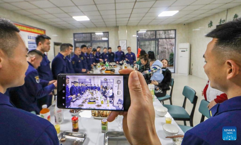 Firefighters and their family members pose for a group photo during a feast on the eve of the Spring Festival in Cengong County of Qiandongnan Miao and Dong Autonomous Prefecture, southwest China's Guizhou Province, Jan. 21, 2023. (Photo by Luo Hui/Xinhua)