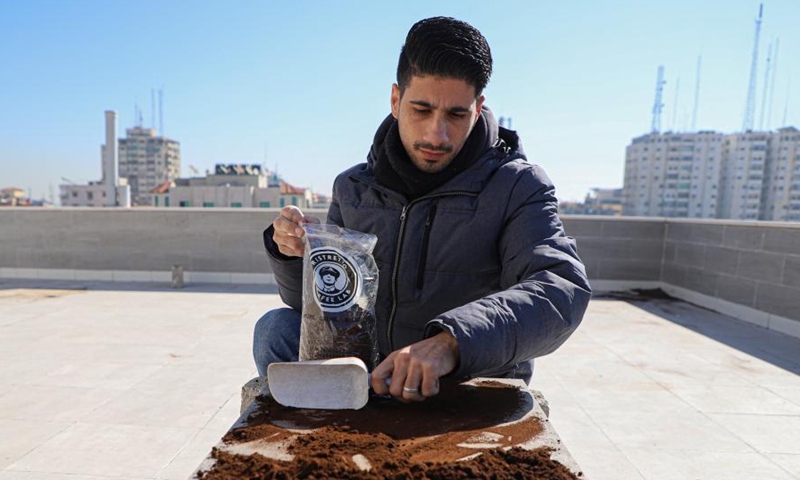 Abdullah al-Safadi collects coffee grounds to use them as fertilizer for plants in Gaza City, on Jan. 19, 2023. Abdullah al-Safadi, a Gazan young man in his 20s, has been promoting the recycling of coffee grounds into organic fertilizer in his community. (Photo by Rizek Abdeljawad/Xinhua)